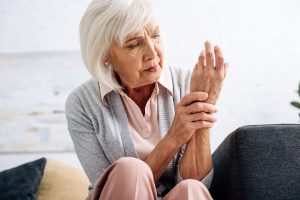 An elderly woman holding her wrist in pain.