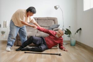 A young man helping a senior who fell