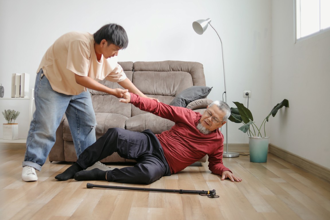 A young man helping a senior who fell